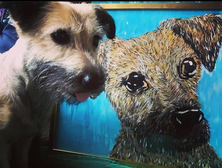 Kistestű terrier kék hátterű festmény mellett